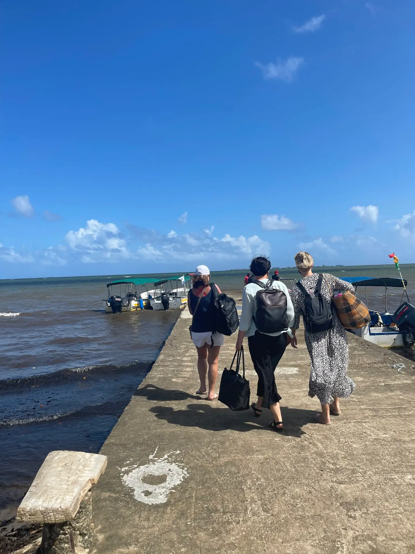 The backs the three women on a cement dock, headed to board a boat to the San Blas Islands