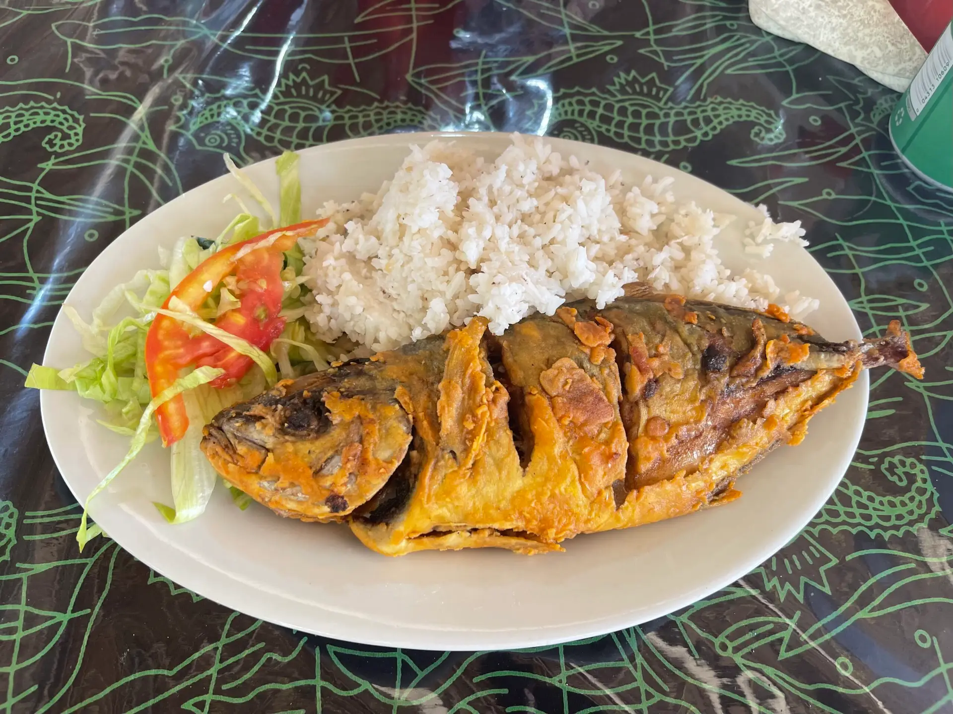 A heavily breaded piece of wild-caught white fish over white rice on a plate.