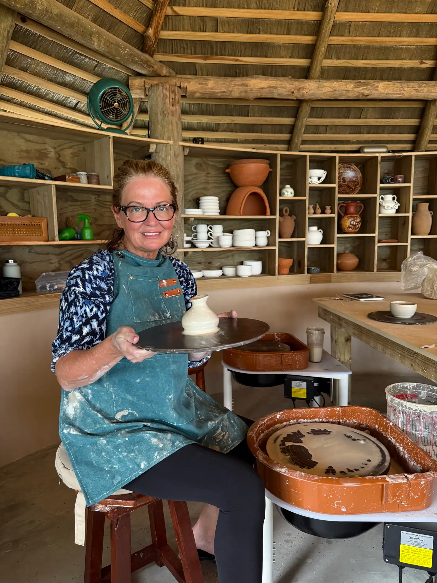 Shiloh + Bella Founder Anne Marie at the pottery wheel showing off the small vase she just made.
