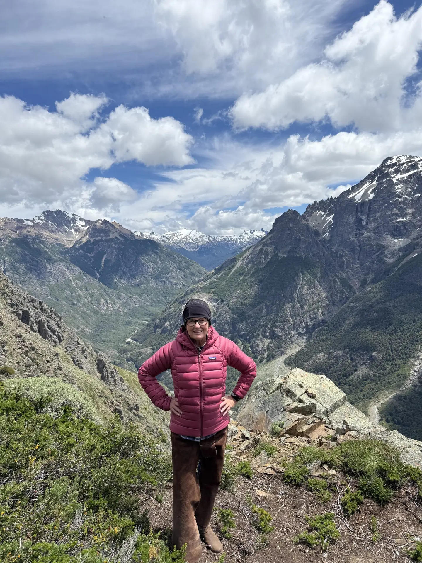 The author posing on the side of a mountain in Argentina with vast peaks of other Patagonian mountains in the background
