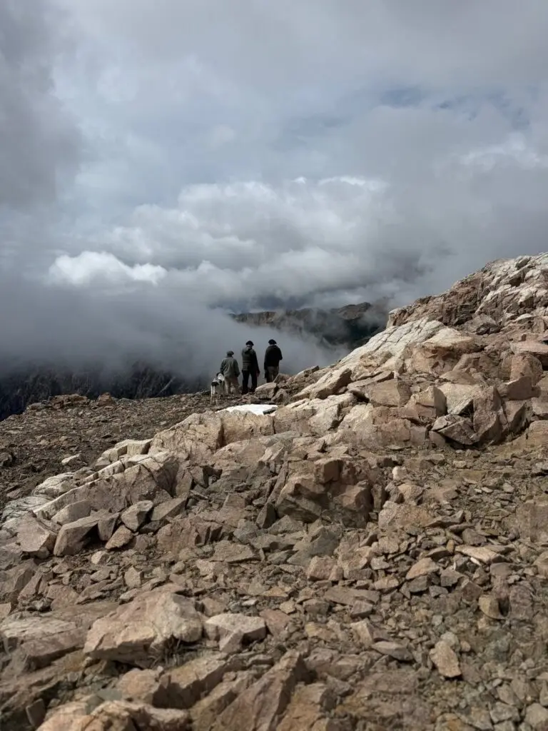 High in the clouds of the Patagonia mountains, three men in distance looking across the range