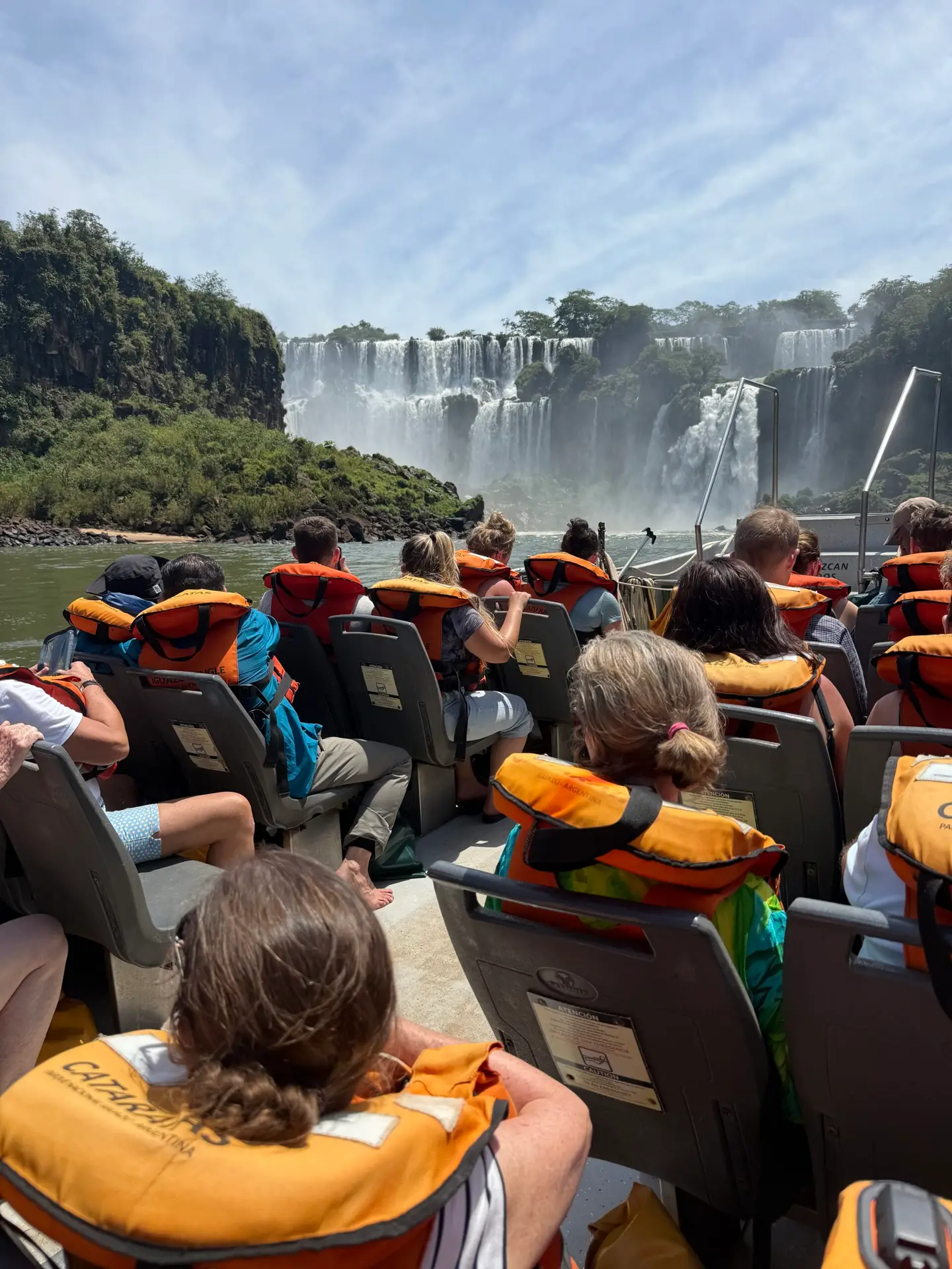 Tour boat filled with passengers in life vests preparing to drive under the massive waterfalls that are considered one of the three best in the world.
